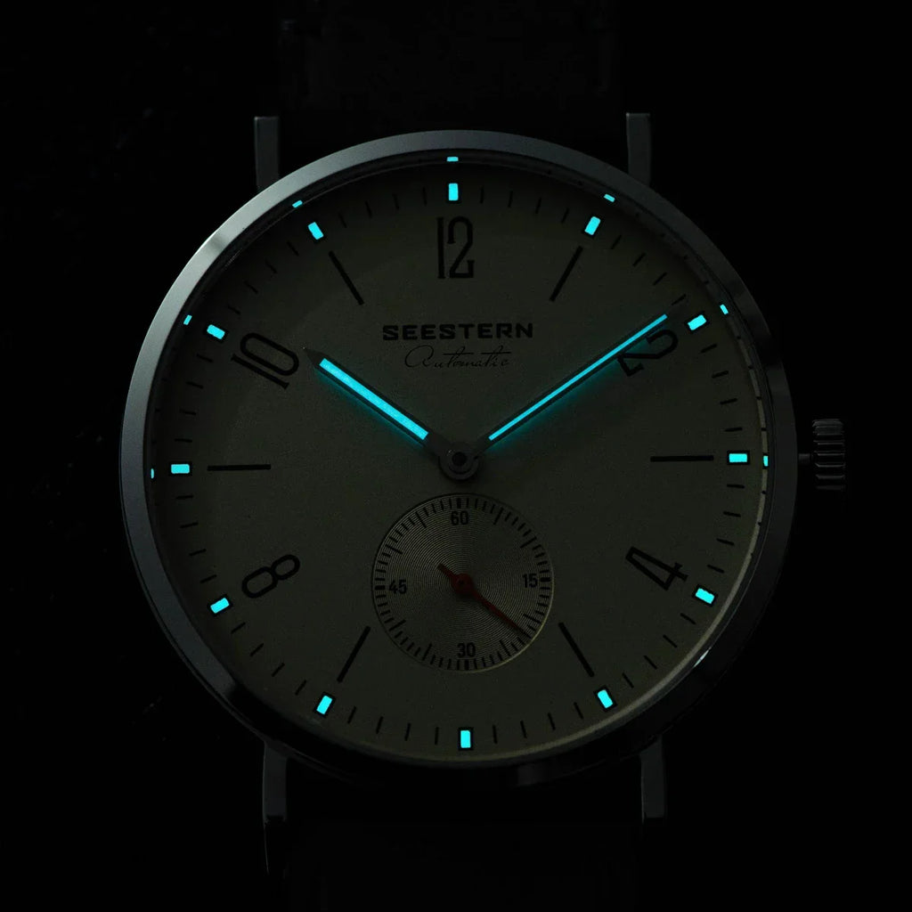 Close-up of Seestern Automatic watch with glowing blue hands and hour markers in dark