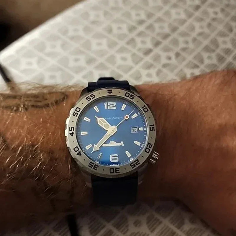 Blue dial Vostok Amphibia wristwatch with silver bezel and black strap on hairy wrist