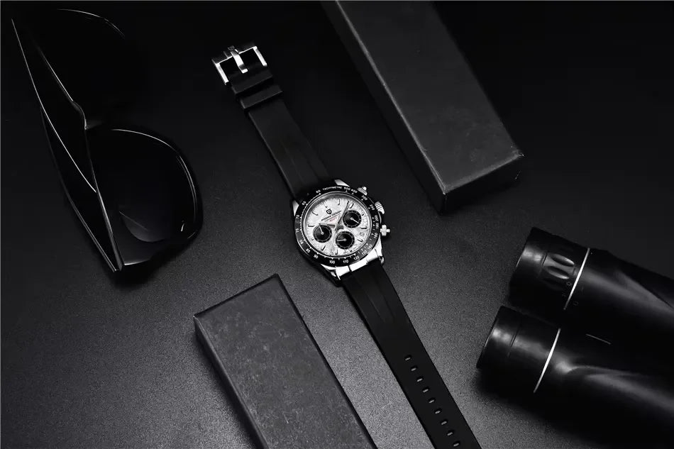 Black sport watch with silver dial, black strap, beside black sunglasses and binoculars on dark surface