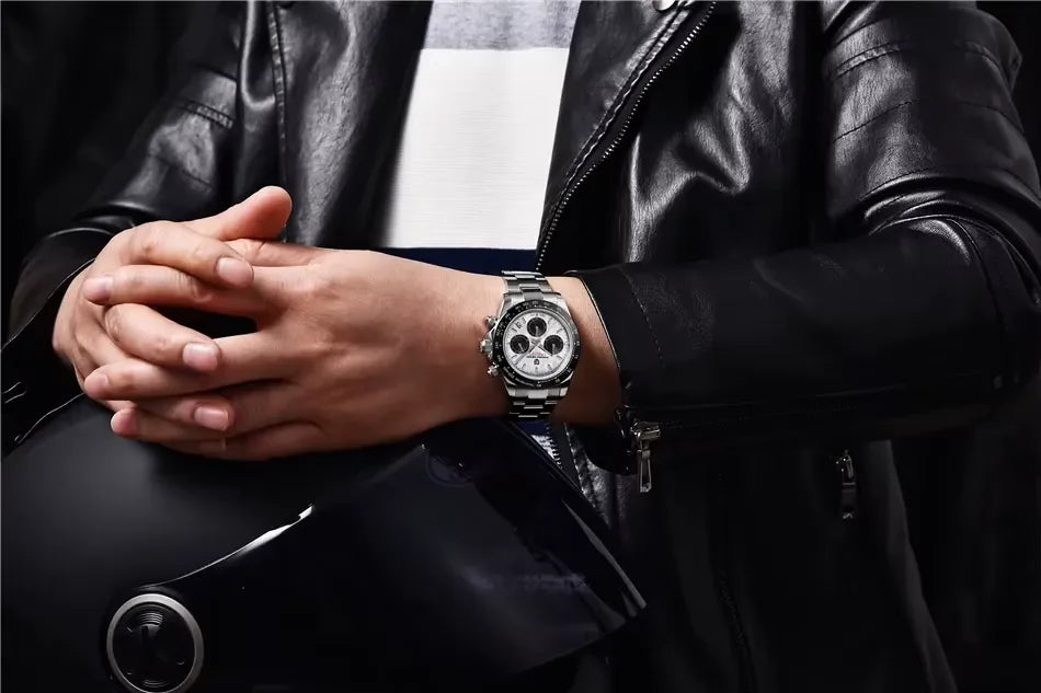 Person wearing a silver chronograph wristwatch with a white dial and black subdials, dressed in a black leather jacket
