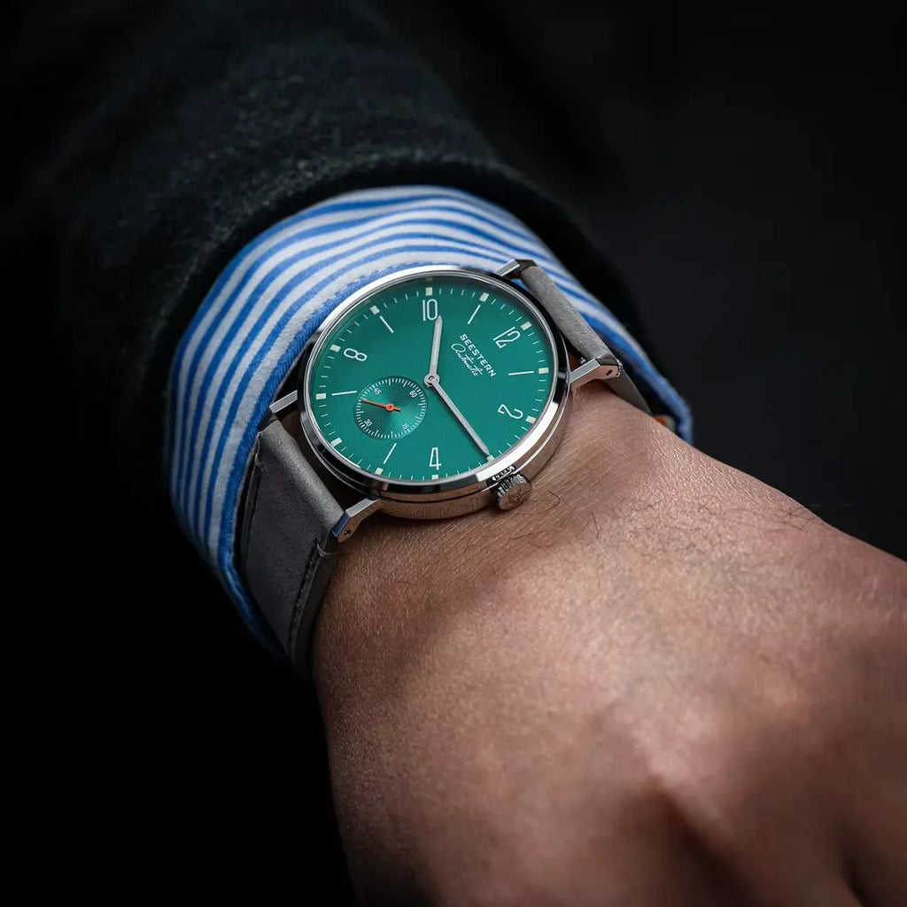 Close-up of wrist wearing a green dial SESTERN wristwatch with silver case and grey leather strap